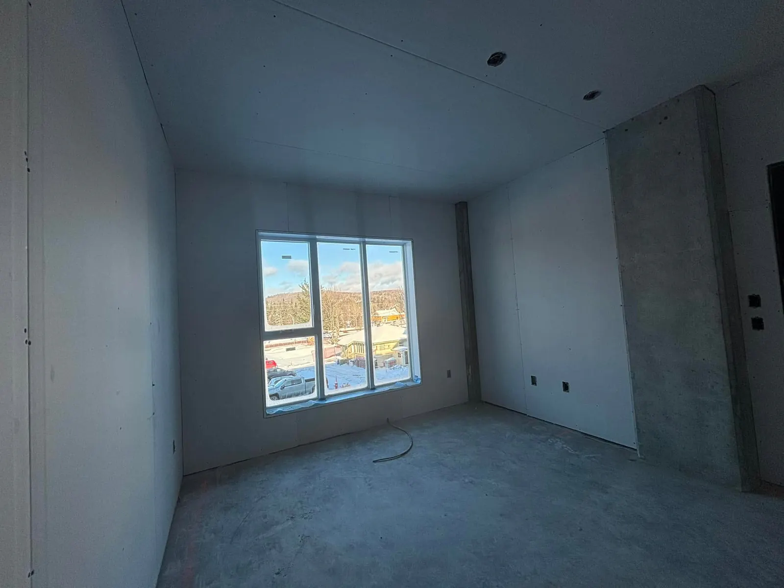 Chambre d'un logement avec murs et plafond en gypse et grande fenêtre